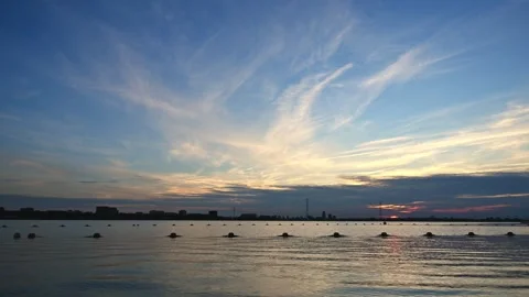 Time lapse video of clouds at sunset over the sea with urban skyline in the 動画素材 339152406