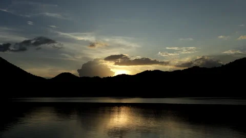Time-lapse video of colorful clouds rolling over a lake, .with blue mountai.. Video stock 319839136