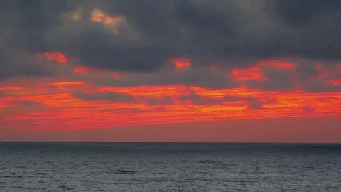 Time lapse video of dramatic red sunset over the ocean with dark clouds in 4k Vídeo Stock 282337734