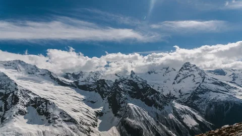 Time lapse video of snow-capped mountains with running clouds on a Sunny day Stock Footage 127944301