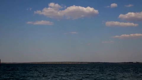 Time-lapse video of a variety clouds floating in a blue sky over water 库存影片 341459096