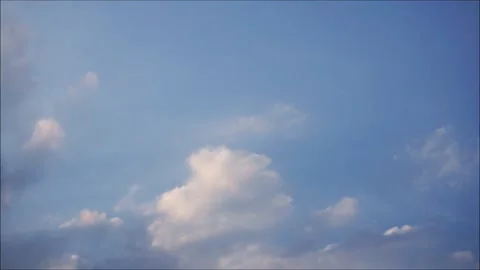 Time-lapse video of white clouds slowly moving across a blue sky with a peaceful Stock Footage 345375742