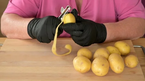 Time lapse video of a womans hands in black gloves to peeling potatoes to make Stock Footage 129193551