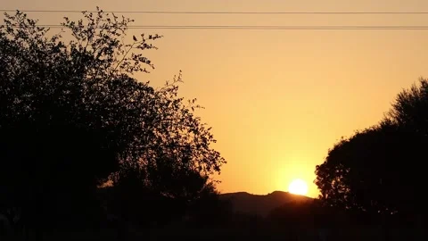 Time lapse of The view of the bright sun rising from behind a silhouette hill Stock Footage 172970175
