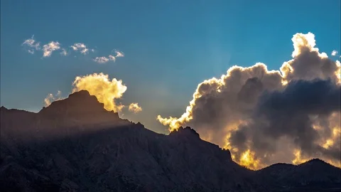 Time lapse view as light rays explode through clouds and shine over jagged 動画素材 99582679