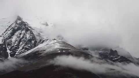 Time lapse view on snowy mountains with moving white clouds hiding and showing Stock Footage 264567378