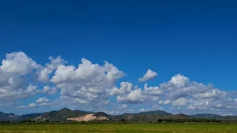 Time lapse view of white cumulus clouds moving fast over mountains and paddy Stock Footage 345507944