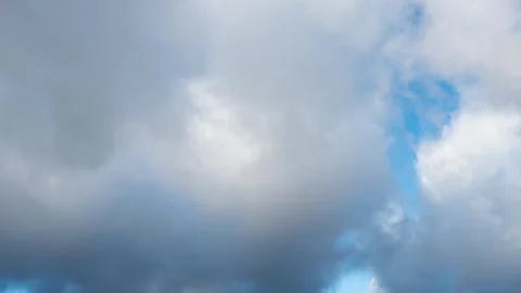 Time lapse of white and dark gray fluffy clouds moving fast in the blue sky Stock Footage 292954238
