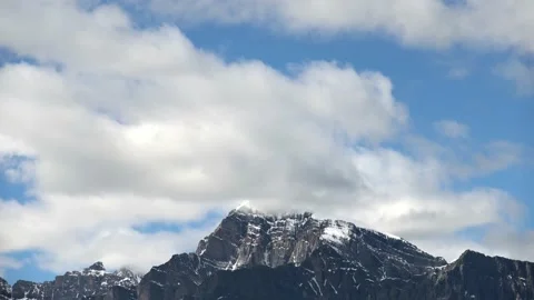 Time lapse of white billowing clouds forming above a large rocky mountain range  Stock Footage 222019279