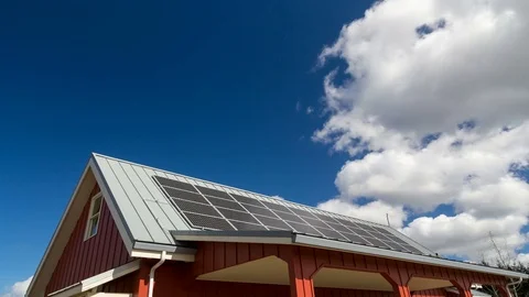 Time lapse of white clouds and blue sky over rooftop with solar panels installed Stock Footage 73672158