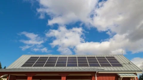Time lapse of white clouds and blue sky over rooftop with solar panels installed Stock Footage 73672203