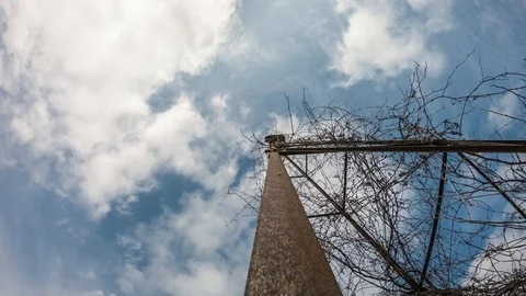 Time lapse white clouds on blue sky above old rusted tower in foreground. Stock Footage 128437093
