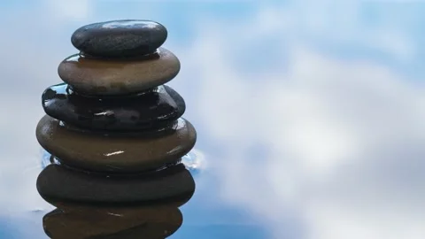 Time lapse of white clouds in blue sky reflecting on water with balance stones Stock Footage 138917513