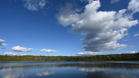 Time lapse of white clouds in a blue sky moving above a large lake Stock Footage 219484672