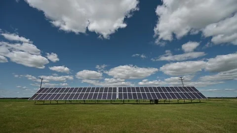 Time lapse of white clouds in a blue sky moving above an array of solar panels  Stock Footage 245653083