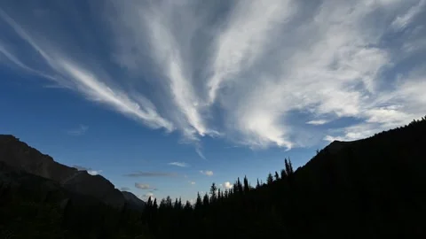 Time lapse of white clouds in a blue sky above mountains and trees.  Stock Footage 246865077
