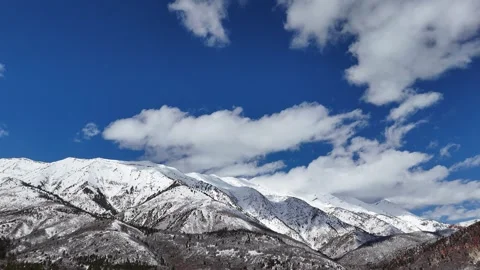 Time lapse-White clouds move slowly over snowy mountain top Stock Footage 267044224