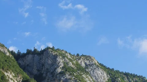 Time-lapse of white clouds moving over the top of a rocky mountain Stock Footage 109294065
