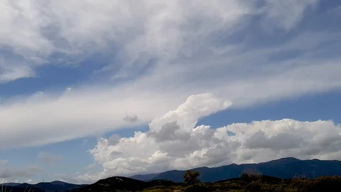 Time lapse of white clouds moving fast over hills Stock Footage 112652749