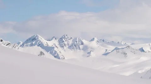 Time-lapse of white clouds moving over snowy mountain ranges Stock Footage 113254624