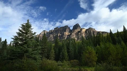 Time lapse of white clouds moving through a blue sky above large mountain Stock Footage 138711353