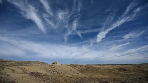 Time lapse of white clouds moving through a blue sky above dry desert grass Stock Footage 297400714