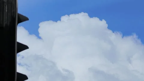 Time lapse of white cumulus clouds against deep blue sky behind a traffic light Video stock 347943321