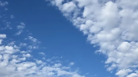 Time lapse of white fluffy clouds moving through a bright blue sky Stock Footage 327920903