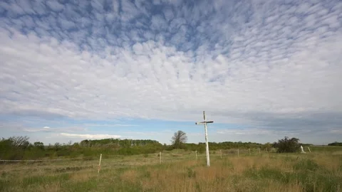 Time lapse of white puffy clouds in a blue sky above an old overgrown cemetery  Stock Footage 263278389