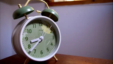 Time-Lapse of a White Retro Alarm Clock on a Wooden Table by an Open Window Stock Footage 338291611