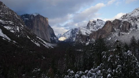 Time lapse wide shot of sunset clouds in blue sky above a snowy Yosemite Valley Stock Footage 145985957