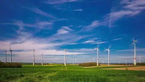 Time lapse of wind turbines on the rapeseed field. Flowing white clouds. Stock Footage 153920567