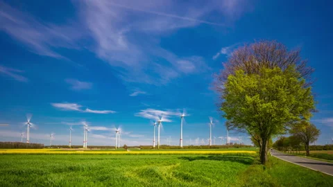 Time lapse of wind turbines on the rapeseed field in bloom. White clouds. Stock Footage 153920975