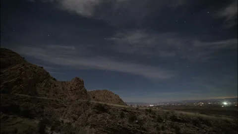 Time lapse of wispy clouds and stars above a desert valley and mountains Stock Footage 331357962