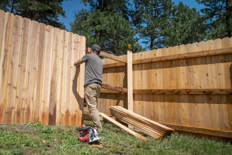 Time-Lapse of Worker Building Cedar Fence Between Two Corners Stock Footage 315921034
