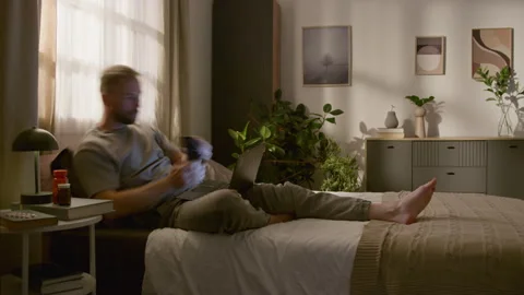Time Lapse of Young Man Waking Up in Bed and Working on Computer from Home Stock Footage 314839752