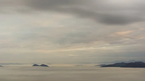 Time lapse zoom out view of clouds moving above with fog bellow Stock Footage 128140885