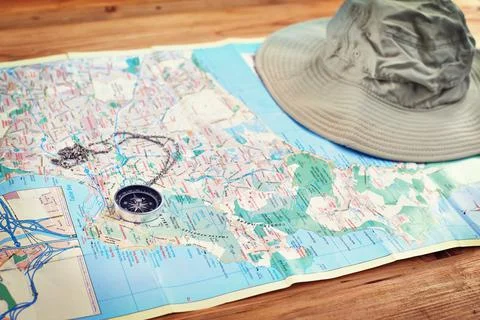Time to make some discoveries. a compass and a hat lying on a map on a table. Stock Photos
