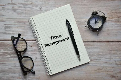 TIME MANAGEMENT text on notebook with pen, spectacles and analog alarm clock. Stock Photos