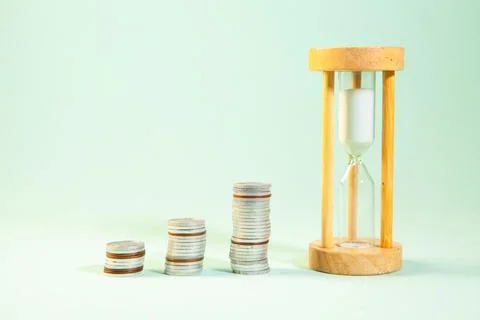 Time is money concept, coin stack with hourglass on green background Stock Photos