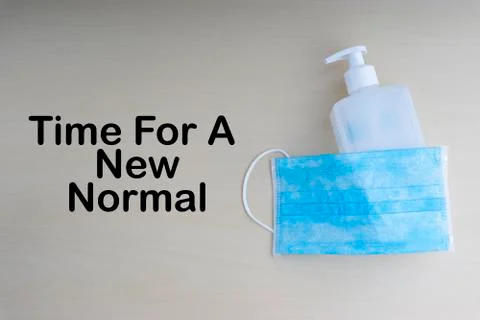 TIME FOR A NEW NORMAL text with face mask and hand sanitizer on wooden backgr 库存照片