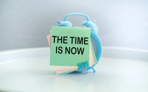 The time is now text on alarm clock concept on notebook Stock Photos
