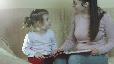 Time only for mother and her little daughter reading book together. Stock Footage 104167127