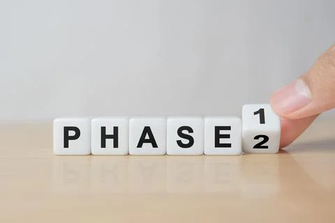 Time for Phase 2. Hand is turning a dice and changes the word 'Phase 1' to .. Stock Photos