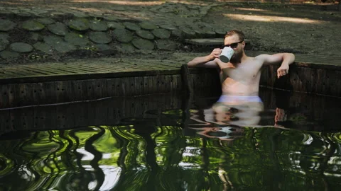 Time to relax. Young bearded man with sunglasses bare torso sitting in swimming Stock-Footage 141539339