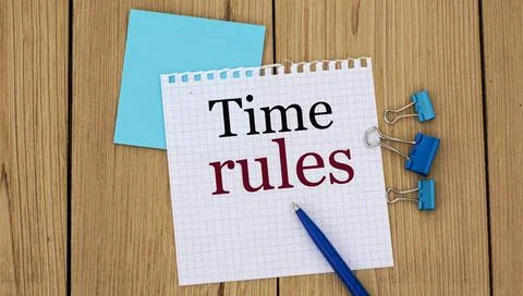 TIME RULES - word written in a notebook on a wooden background with a pen and Stock Photos