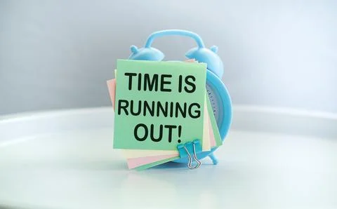 Time is running out is shown using the text and alarm clock Stock Photos
