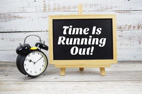 Time Is Running Out! text written on blackboard with alarm clock on wooden .. Stock Photos