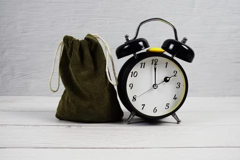 Time to Saving Concept money bag and alarm clock on wooden background Foto stock