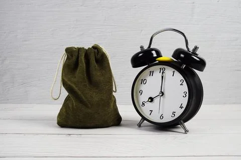 Time to Saving Concept money bag and alarm clock on wooden background Foto stock